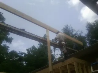 Carpenter setting a ridge beam over a new addition frame — Ice Dam Removal by Roofing Brothers in Montezuma